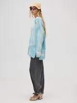 Buzo de algodón con efecto tie-dye en tonos celeste y blanco, de corte holgado y largo por debajo de la cintura, con puños acanalados.
