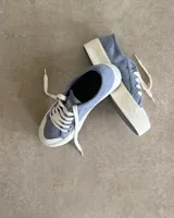Zapatillas de lona celeste con cordones blancos y suela blanca.
