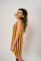 Vestido corto tejido a rayas verticales color amarillo y marrón, con escote redondo y mangas sisa. Incluye cinturón marrón con hebilla dorada.