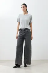 Pantalón de jean gris oscuro, corte wide leg, con tachas plateadas en los laterales.