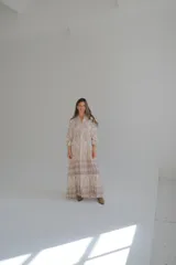 Vestido largo color beige con estampado abstracto en tonos marrones y azules. Tiene cuello mao, mangas largas abullonadas con puños elásticos y falda escalonada.