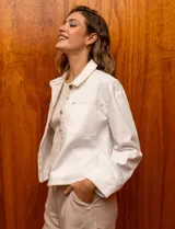 Campera de denim blanca con cuello con solapa, abertura central con botones metálicos y bolsillos delanteros.