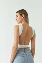 Top blanco sin mangas, con escote redondo y espalda descubierta.