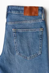 Jean de denim azul con corte slim regular, tiro medio, cinco bolsillos y cierre con cremallera y botón.