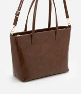 Bolso shopper grande color marrón de material sintético con doble asa, una fija y otra larga desmontable. Tiene cierre de cremallera y detalles de recortes.