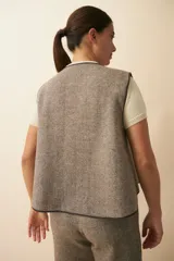 Chaleco marrón con solapas amplias y terminaciones envivadas. Diseño reversible y sin mangas.