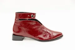 Botín de cuero color borgoña con taco bajo, corte en V en el empeine, pulsera con detalles metálicos y cierre lateral.