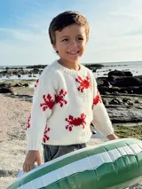 Sweater de lana merino color crudo con diseño de cangrejos rojos bordados a mano.
