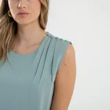 Blusa sin mangas color verde agua, con cuello redondo y detalle de drapeado en el hombro.