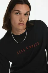 Remera negra de corte holgado con estampado frontal del logo de la banda Guns N' Roses en color rojo.