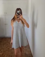 Vestido corto blanco con rayas horizontales negras, escote en V y corte evasé.