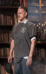 Remera negra con efecto nevado, de manga corta y cuello redondo, con calce oversize. Presenta una estampa en la espalda inspirada en el arcano "La Estrella" del Tarot, con una figura femenina vertiendo agua de dos cántaros, rodeada de estrellas y vegetación en colores vibrantes como amarillo, azul, rosa y verde.