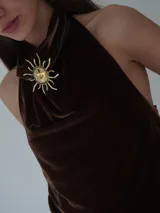 Gargantilla de cuero marrón con dije de sol dorado.