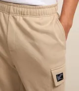Bermuda masculina color beige confeccionada en tela french terry, con cintura elástica, cordón interior para ajustes y bolsillos cargo.