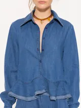 Camisa de denim liviano color azul, con ruedo curvo, canesú en forma de V en la espalda y acceso mediante botones.