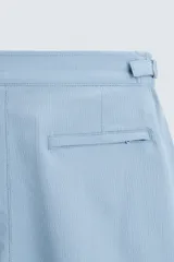 Short de baño celeste de tejido técnico con cintura elástica ajustable con cordón interior y trabillas laterales. Tiene bolsillos frontales y bolsillo trasero con cierre de cremallera. Cuenta con forro interior y cierre frontal con cremallera y botón a presión oculto.