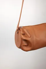 Bandolera de cuero color marrón, con correa larga regulable y cierre superior.