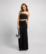 Blusa cropped con escote strapless, confeccionada en tul metalizado con brillos aplicados y cierre track.