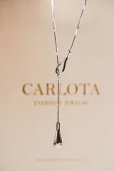 Collar plateado de acero quirúrgico con dije en forma de lazo fluido.