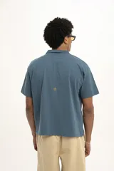 Remera estilo rugby a rayas horizontales verdes y blancas, con cuello blanco tipo polo y mangas cortas. Tiene un logo bordado en el pecho.