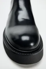 Botín Chelsea de cuero negro con elásticos laterales, tirador trasero y suela track con plataforma.
