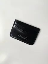 Tarjetero negro de cuero vacuno con el logo 'Cilento' grabado en el frente. Cuenta con cuatro divisiones para tarjetas y un bolsillo central.