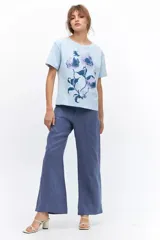 Remera lila de algodón con estampado de flores en tonos naranja y rosa.