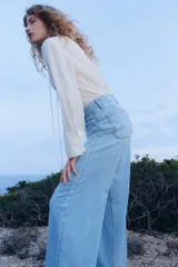 Blusa blanca de corte holgado en tejido transparente de mezcla de lyocell. Modelo de manga larga con cuello elevado de encaje, puños anchos abotonados y bajo recto. Pechera con abertura, alforzas y tiras spaghetti.
