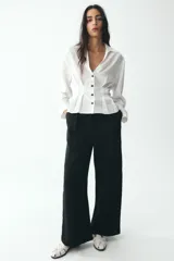 Pantalón negro de tiro alto con bolsillos delanteros, pinzas y corte ancho.