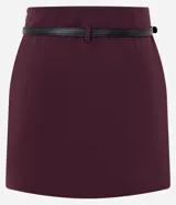 Short pollera de sastre color bordó, con cintura con trabillas y textura plisada. Incluye un cinturón fino de material sintético negro.