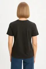 Remera blanca de algodón con cuello redondo y mangas cortas. Estampado con moños plateados brillantes.