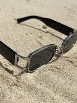 Gafas de sol rectangulares con montura plateada y lentes grises.
