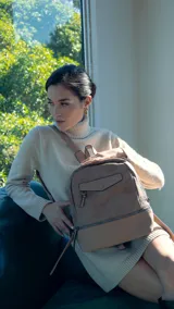 Mochila color marrón con bolsillo ojal al frente con cierre y broche. Apertura superior. Cierres con tiradores en mismo tono. Incluye bolsillos internos. Correas para colgar en la espalda regulable con hebilla, asa de mano.