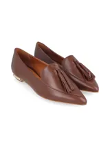 Zapato mocasín color caramelo, de cuero, con punta fina y detalle de borlas. Tiene un pequeño taco cuadrado dorado.