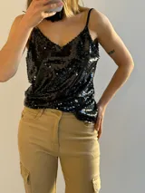 Musculosa negra con lentejuelas y tirantes finos.
