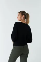 Sweater verde de punto liviano con textura acanalada y diseño de hombros caídos.