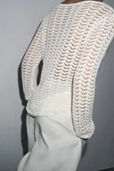 Jersey de punto calado color blanco, con cuello barco y manga larga.