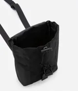 Bolso mini tipo bucket color negro, hecho en poliamida sin estampa. Tiene cierre delantero con tirador y cordón elástico, y tapa con enganche.