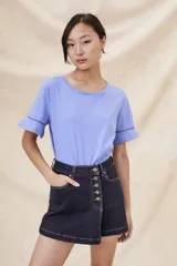 Remera blanca de algodón con cuello redondo y mangas cortas con volado y detalle de puntilla calada.