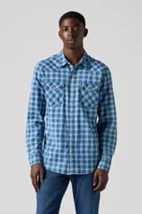 Camisa de hombre de manga larga, con estampado a cuadros en tonos azules y blancos. Tiene dos bolsillos en el pecho con solapa y cierre de botón a presión.