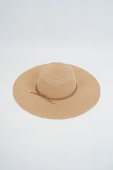 Sombrero de paja tejido color beige, de ala ancha y copa redonda, con cinta decorativa de cuero marrón claro.