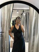 Vestido largo de silueta fluida confeccionado en seda con detalles de encaje. Presenta un diseño negro con estampado de lunares blancos, escote en V profundo y espalda descubierta con tiras cruzadas. La falda cuenta con paneles de encaje que aportan movimiento y delicadeza.