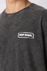 Remera gris oscuro con efecto gastado, de algodón peinado, con cuello redondo y estampado pequeño en el pecho.