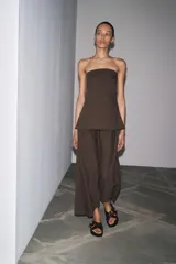 Vestido midi marrón confeccionado en hilatura 24% de lino. Escote recto y hombros descubiertos. Cierre en espalda con cremallera oculta en costura.