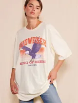 Remera oversize color crema con estampado gráfico de un águila volando y el texto "BUDWEISER KING OF BEERS SINCE 1876" en tonos naranja y rojo.