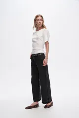 Pantalón jean negro de corte recto, tiro medio y ruedo desflecado.