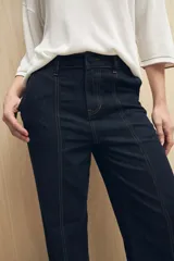 Pantalón de jean azul oscuro, de corte recto y tiro alto, con costuras a la vista.