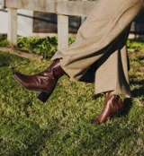 Bota corta color crema con textura de reptil, caña media, punta cuadrada, cierre lateral y taco de madera.