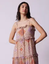 Vestido midi de gasa estampada con motivos geométricos en tonos naranja, lila y beige. Tiene breteles finos regulables, escote en V con volados y falda asimétrica con volados.
