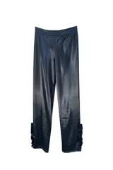 Pantalón de tiro medio color negro metalizado, de calce recto y detalle de volados en la botamanga.
